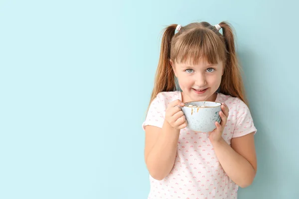 Menina bonito beber chocolate quente no fundo de cor — Fotografia de Stock