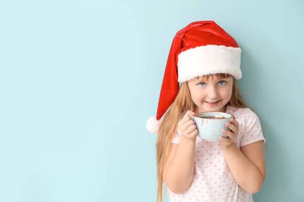 Cute little girl drinking hot chocolate on color background — Stock Photo, Image