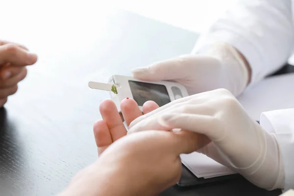 Лікар перевіряє рівень цукру в крові у пацієнта з діабетом у клініці, крупним планом — стокове фото