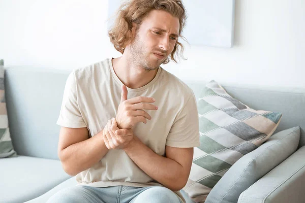 Young man suffering from pain in wrist at home — Stock Photo, Image