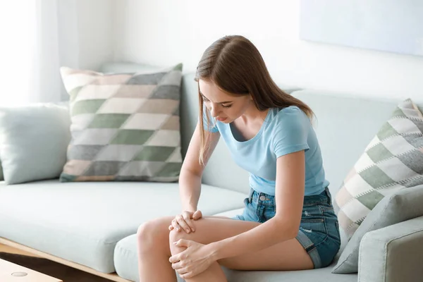 Young woman suffering from pain in knee at home — Stock Photo, Image