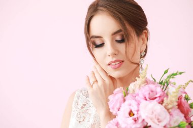 Renkli arka planda düğün buketi ile güzel genç gelin portresi