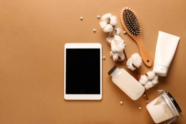 Saç fırçası ve renk arkaplanında kozmetik ürünleri olan modern tablet bilgisayar