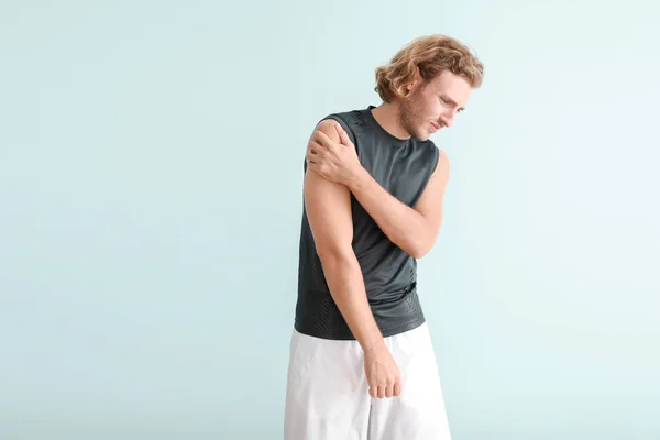 Jonge man lijden aan pijn in de schouder op kleur achtergrond — Stockfoto