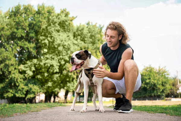 Sportlicher junger Mann mit süßem Hund im Park — Stockfoto