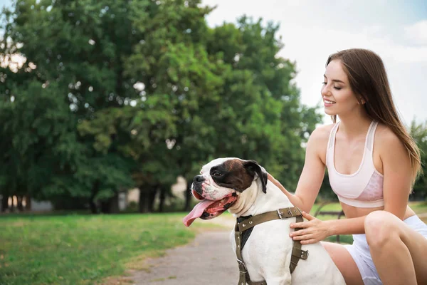 Sporty young woman with cute dog in park — Stock Photo, Image