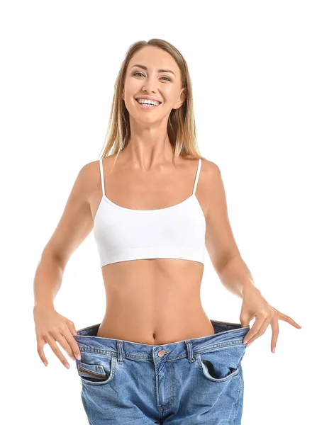 Beautiful young woman in loose jeans on white background. Weight loss concept — ストック写真