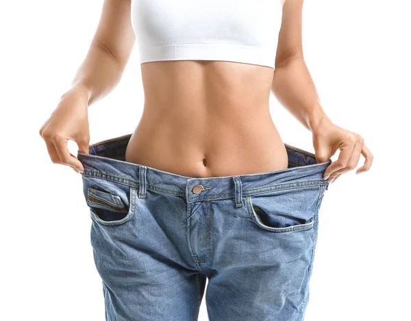 Beautiful young woman in loose jeans on white background. Weight loss concept — ストック写真