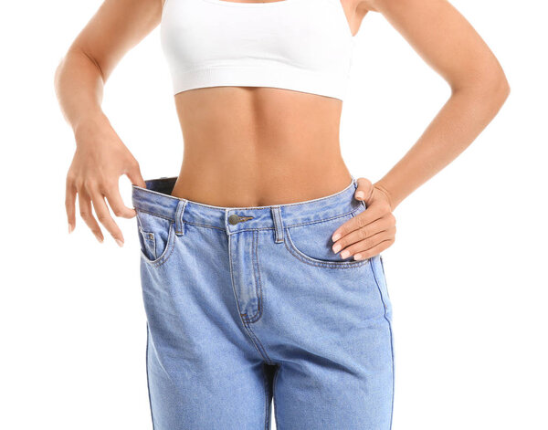 Красивая молодая женщина в джинсах на белом фоне. Концепция потери веса

