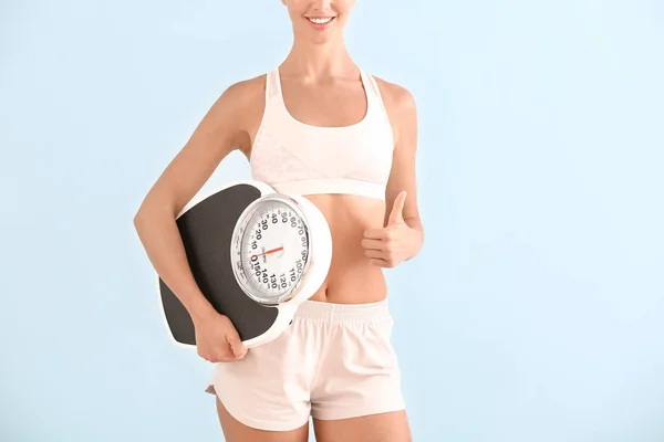 Beautiful young woman with scales on color background. Weight loss concept — Stock Photo, Image