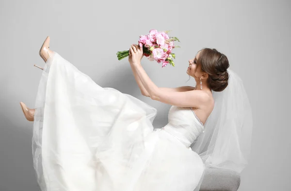 Портрет красивої молодої нареченої з весільним букетом на сірому фоні — стокове фото