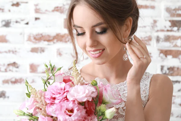 Портрет красивої молодої нареченої з весільним букетом на цегляному фоні — стокове фото