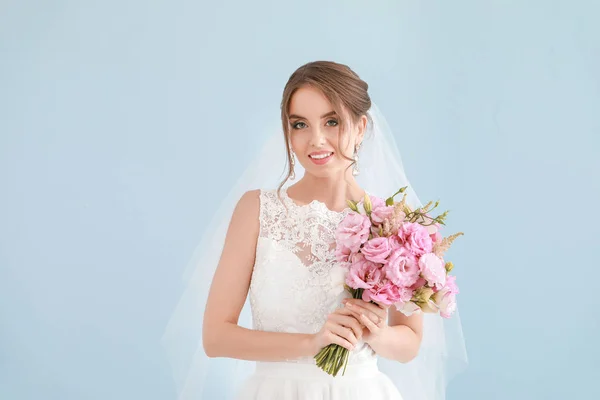 Porträt der schönen jungen Braut mit Brautstrauß auf hellem Hintergrund — Stockfoto