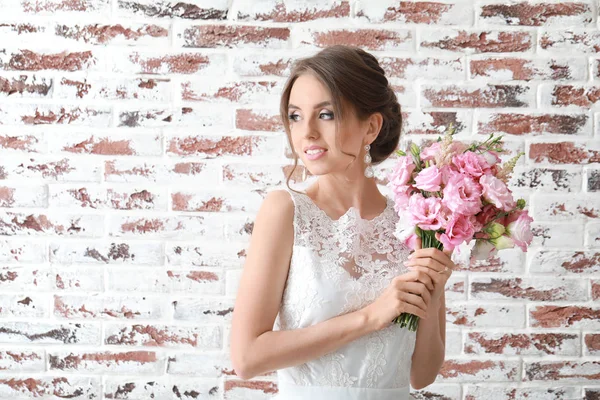 Tuğla arka planda düğün buketi olan güzel gelinin portresi