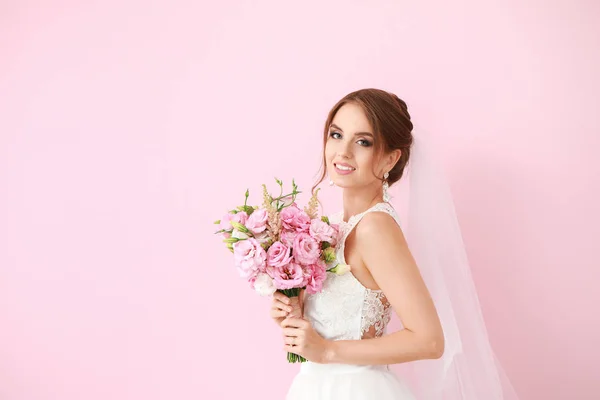 Portret van mooie jonge bruid met bruiloft boeket op kleur achtergrond — Stockfoto