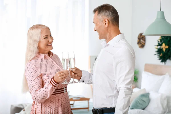 Mature couple with glasses of champagne celebrating Christmas at home — Stock Photo, Image