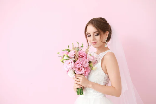 Portret van mooie jonge bruid met bruiloft boeket op kleur achtergrond — Stockfoto