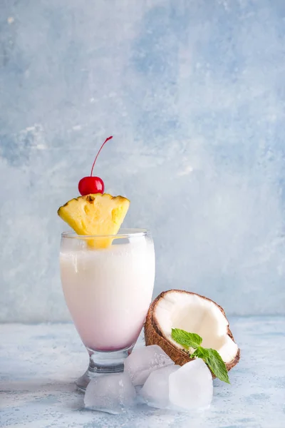 Copa de sabroso cóctel Pina Colada, cubitos de hielo y coco en la mesa —  Fotos de Stock