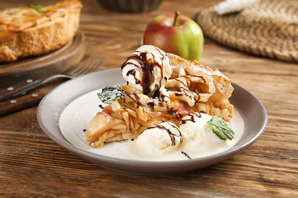 Plate with slice of tasty apple pie and ice cream on wooden table — Stock Photo, Image