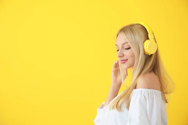 Beautiful young woman listening to music on color background — Stock Photo, Image