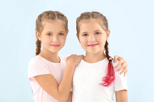 Portrét roztomilé dvojčata dívky na barevném pozadí — Stock fotografie