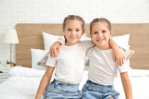 Portret van schattige tweeling meisjes zitten op bed thuis — Stockfoto