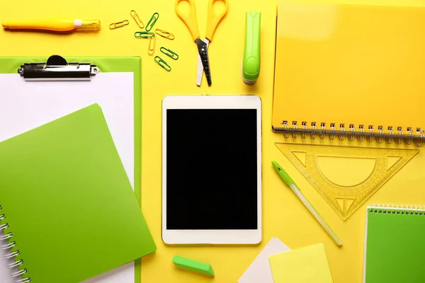 Modern tablet computer with stationery on color background — Stock Photo, Image