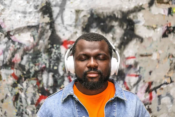 Handsome African-American man listening to music outdoors — Stock Photo, Image