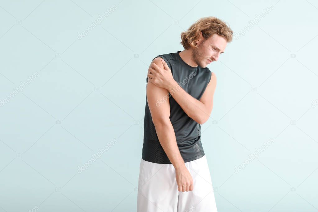 Young man suffering from pain in shoulder on color background