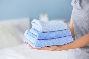 Yatak odasında temiz havluları olan kadın hizmetçi, yakın plan.