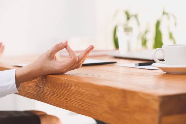 Genç iş kadını ofiste meditasyon yapıyor.