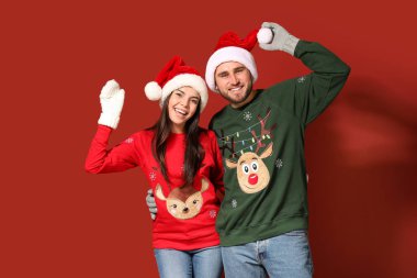 Noel süveteri ve Noel Baba şapkası giyen genç bir çift.