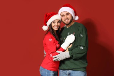 Noel süveteri ve Noel Baba şapkası giyen genç bir çift.