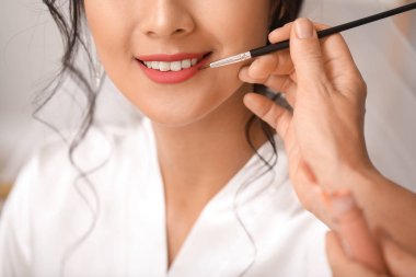 Profesyonel makyaj sanatçısı evde genç Asyalı gelin ile çalışan, closeup