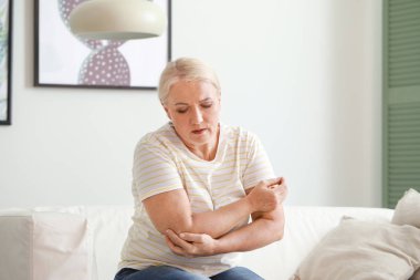 Evde dirsek ağrısı çeken olgun bir kadın.