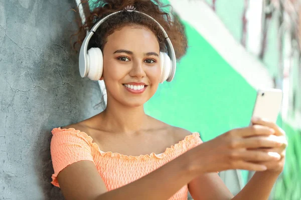 Beautiful African-American with mobile phone listening to music outdoors — Stock Photo, Image