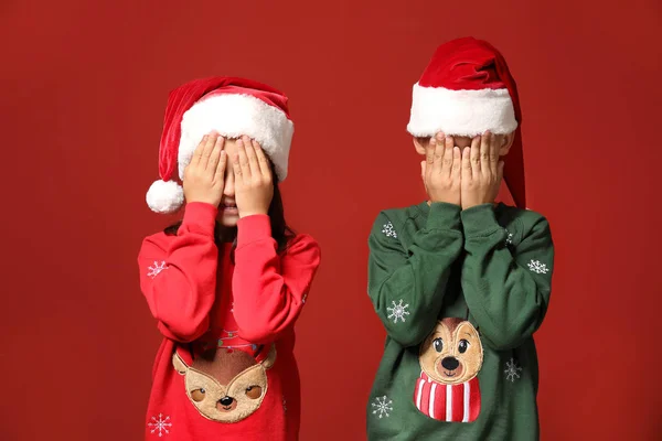 Söta barn i jultröjor och Santa hattar på färg bakgrund — Stockfoto