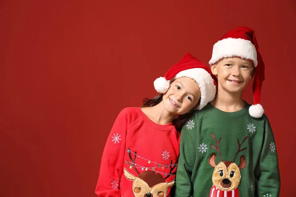 Söta barn i jultröjor och Santa hattar på färg bakgrund — Stockfoto