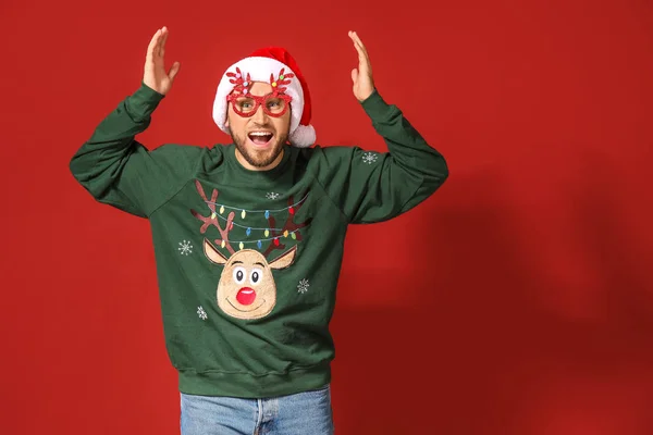 Смешной человек в рождественском свитере и шляпе Санты на цветном фоне — стоковое фото