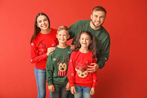 Щаслива сім'я в різдвяних светрах на кольоровому фоні — стокове фото