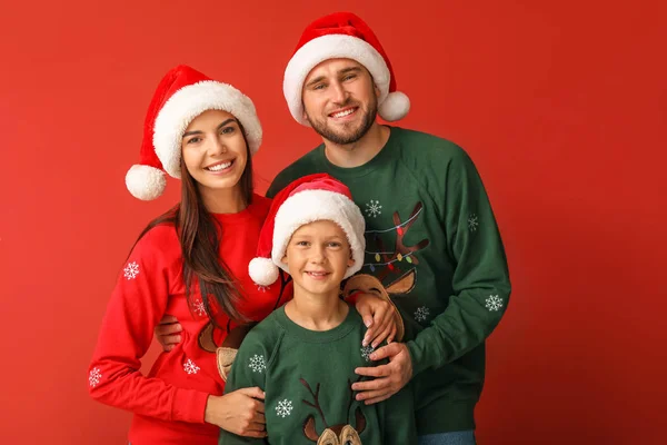 Familia feliz en suéteres de Navidad y sombreros de Santa sobre fondo de color — Foto de Stock