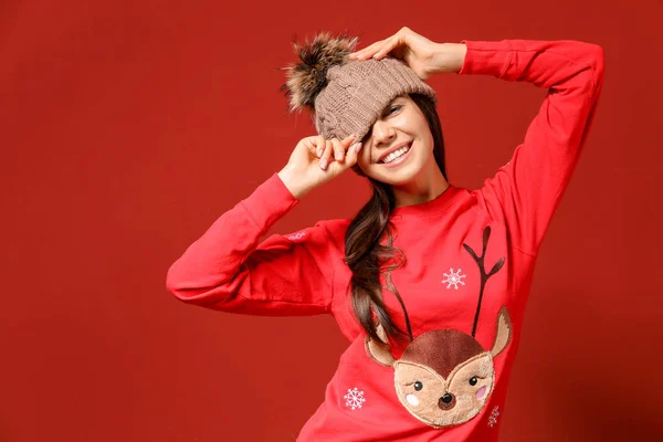 Young woman in Christmas sweater and knitted hat on color background — Stock Photo, Image