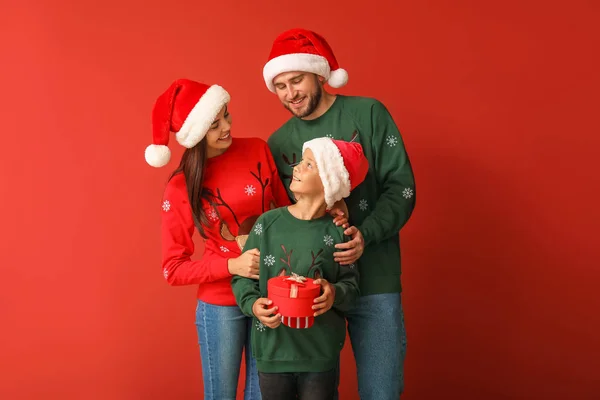 Familia feliz en suéteres de Navidad y sombreros de Santa sobre fondo de color — Foto de Stock