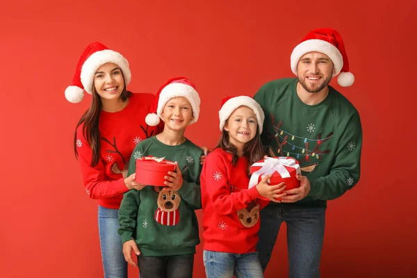 Happy family with Christmas gifts on color background — Stock Photo, Image