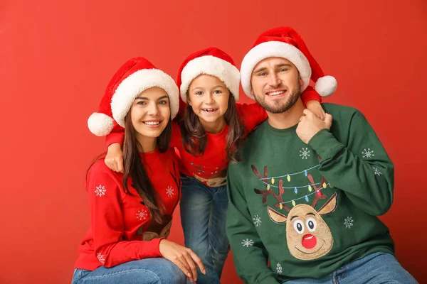 Щаслива сім'я в різдвяних светрах і капелюхах на кольоровому фоні — стокове фото