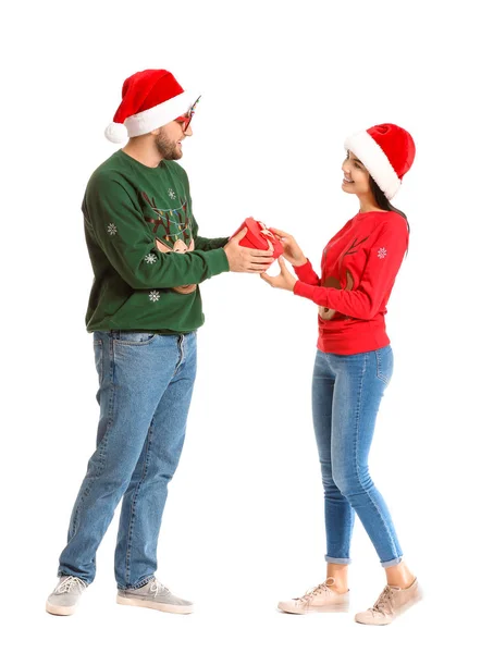 Young couple in Christmas sweaters and with gift on white background — Stock Photo, Image
