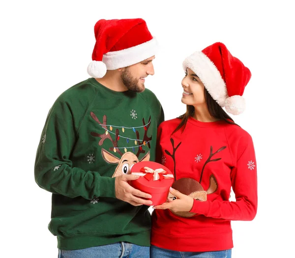 Νεαρό ζευγάρι με χριστουγεννιάτικα πουλόβερ και με δώρο σε λευκό φόντο — Φωτογραφία Αρχείου