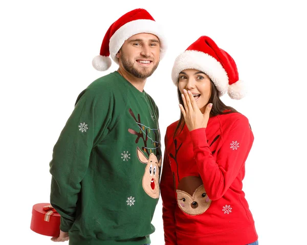 Молода пара в різдвяних светрах і з подарунком на білому тлі — стокове фото
