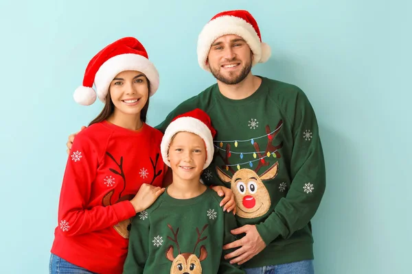 Ευτυχισμένη οικογένεια σε χριστουγεννιάτικα πουλόβερ και καπέλα Σάντα στο φόντο χρώμα — Φωτογραφία Αρχείου