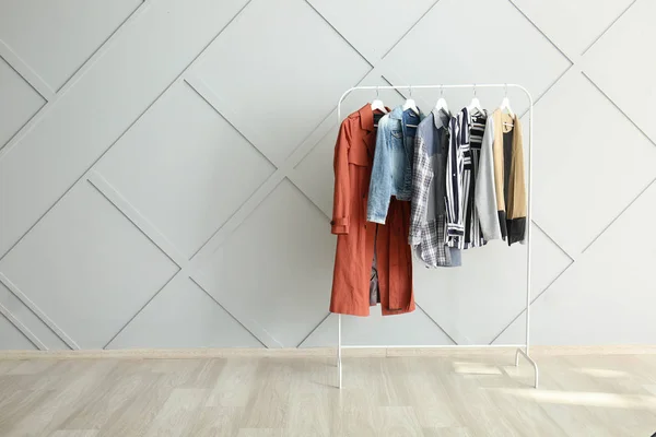 Rack dengan pakaian menggantung dekat dinding cahaya — Stok Foto